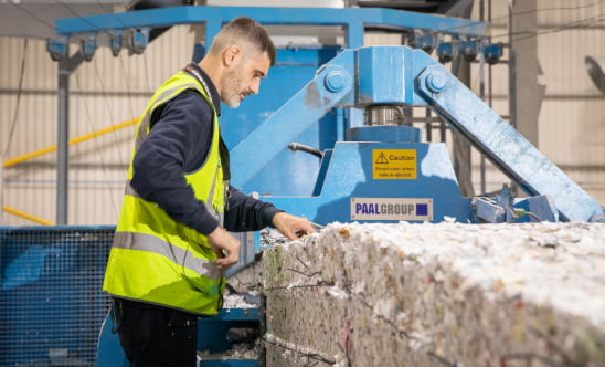 A datashred operative processing a shredded paper bale