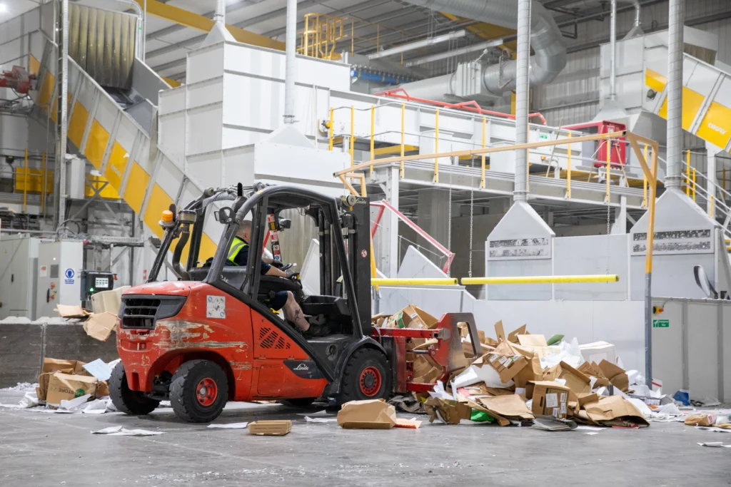 Man on forklift processing cardboard for recycling