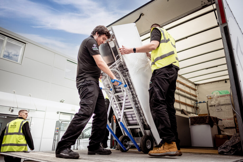 two men loading laboratory equipment into van as part of relocation