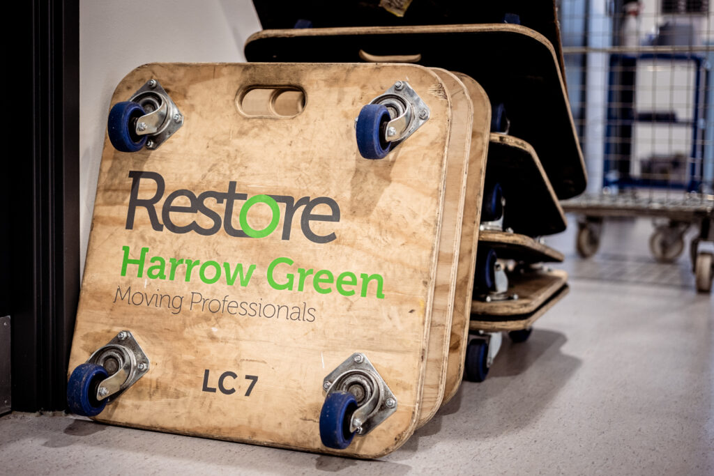 Wooden moving palette on wheels emblazoned with Restore Harrow Green logo